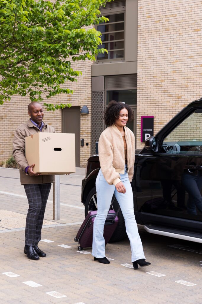 two people walking, carrying luggage as they move house