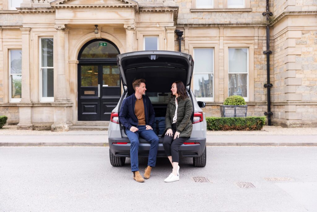 Two people chatting while perching on a car boot