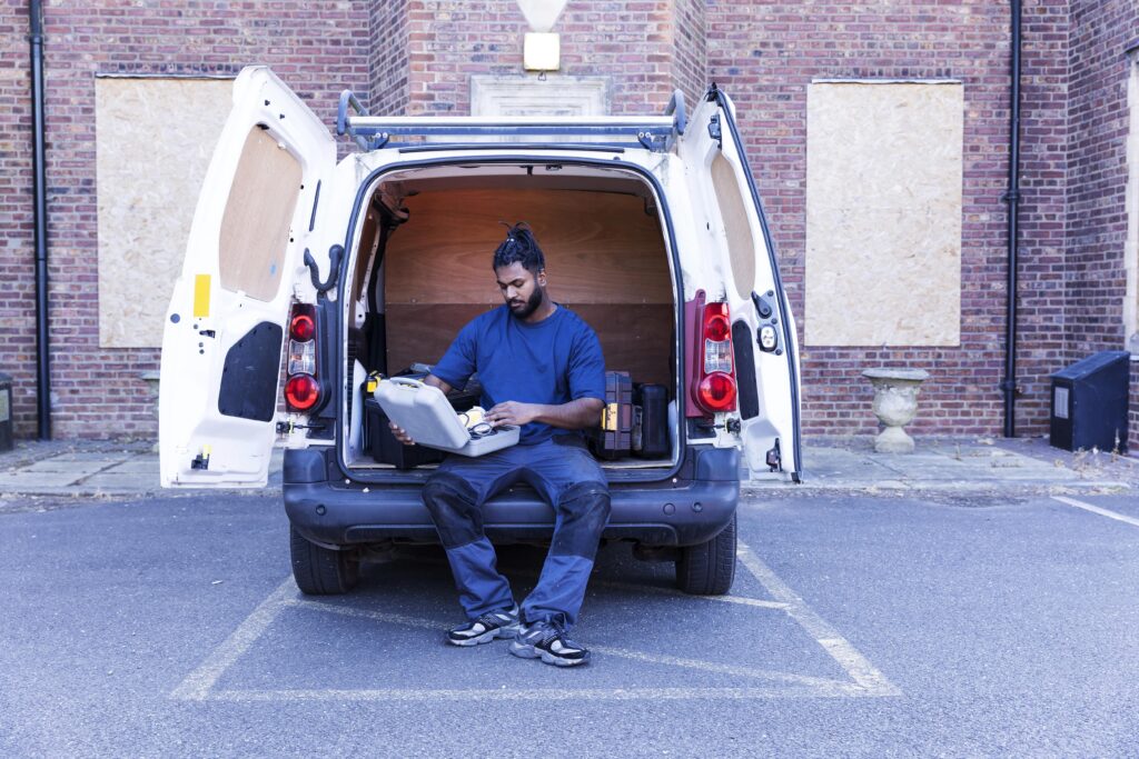 A tradesman checking his tools whilst sitting in the back of his van